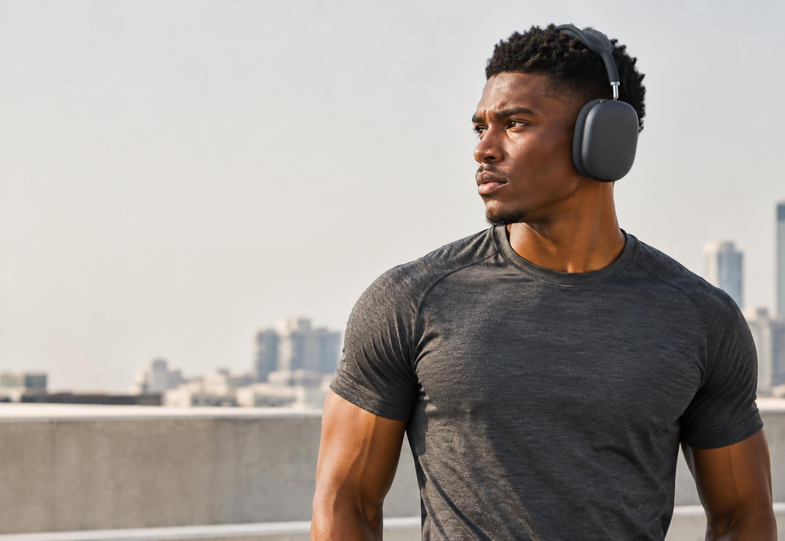 Man in a dark gray shirt wearing black over-ear headphones against the city skyline